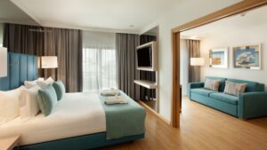 Quarto com cama, televisão e sala de estar com sofá